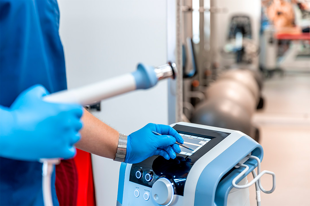 An individual in blue gloves uses an ESWT machine, illustrating patient flow optimization in a busy clinic environment.