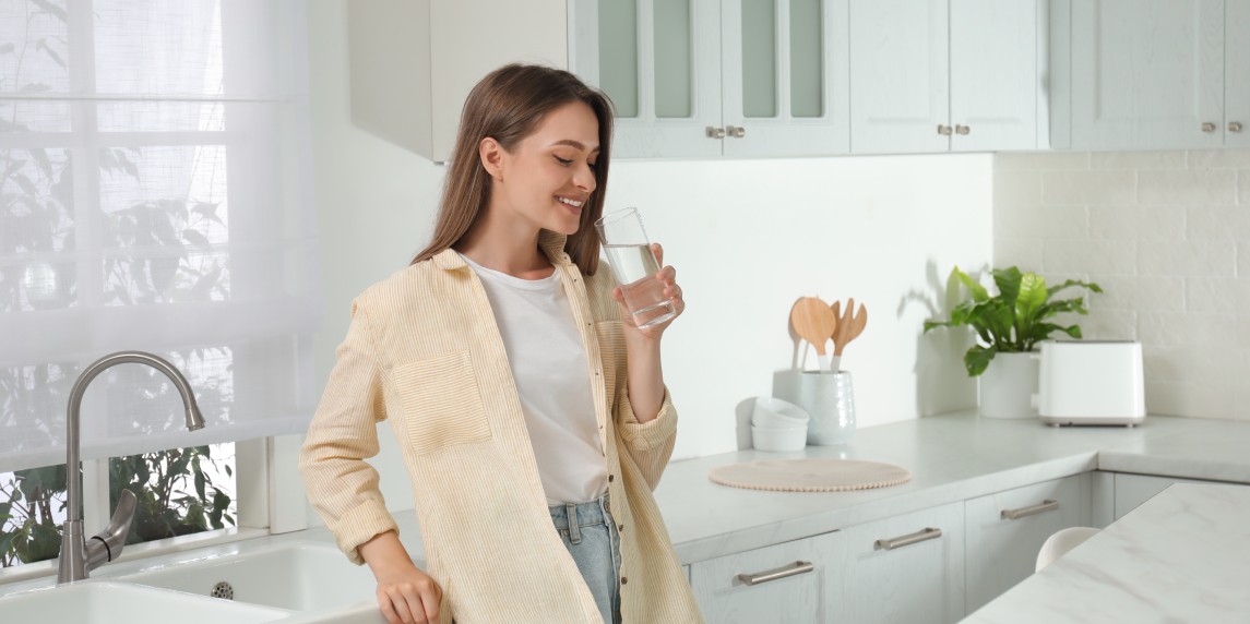 Woman drinking tap water from glass in kitchen