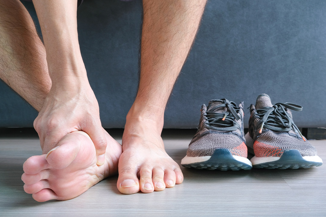 A person’s foot is positioned next to shoes, emphasizing how ESWT is transforming plantar fasciitis treatment in beach settings.