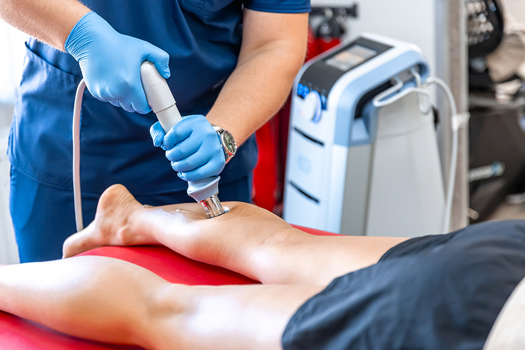  Individual shockwave therapy on leg massage, illustrating a method for managing summer running injuries.