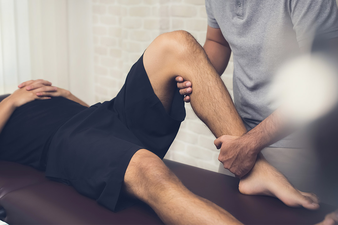 A physical therapist assists a man with an ankle stretch, highlighting techniques for managing summer running injuries.