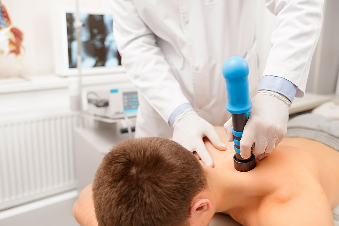 A ypung man receives a shockwave therapy over neck. 