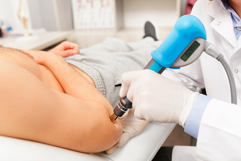 A man undergoing shockwave leasing device therapy on his arm, illustrating the effectiveness of PRP combined with shockwave treatment.