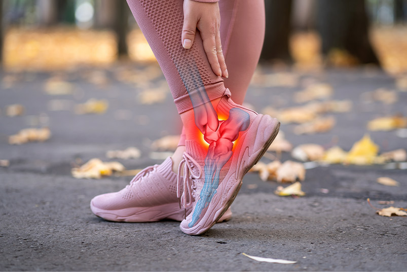 A woman shows discomfort in her foot as she walks along a path, emphasizing the need for effective injury recovery treatments.