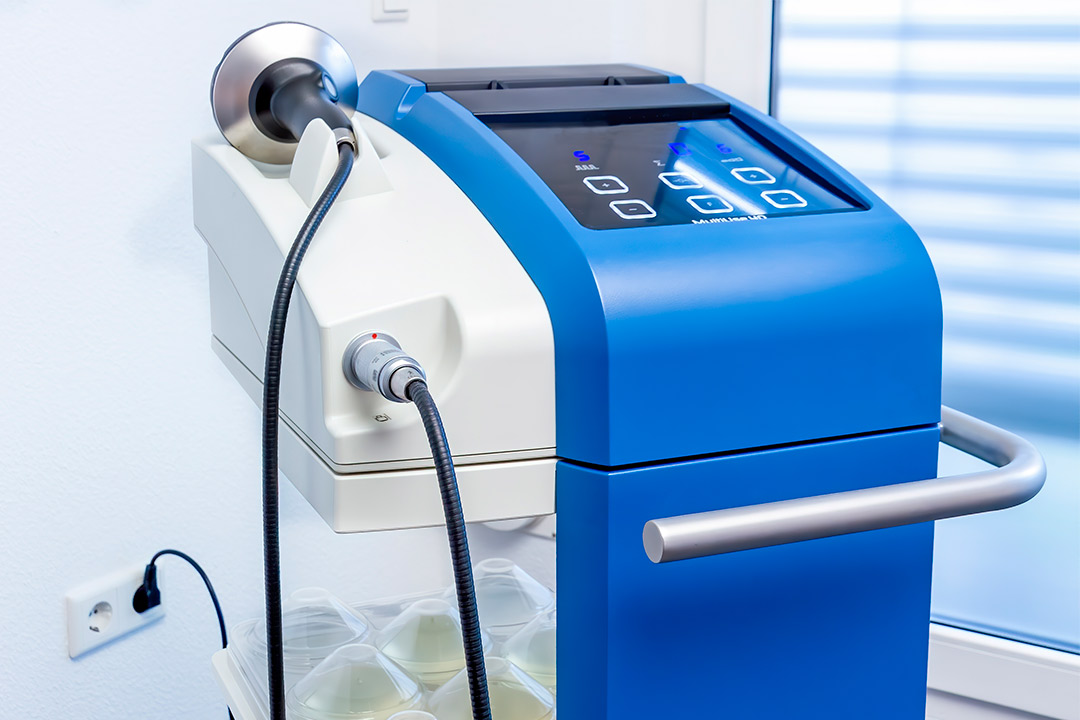 A blue and white machine with an attached hose, related to understanding total costs of shockwave therapy equipment.