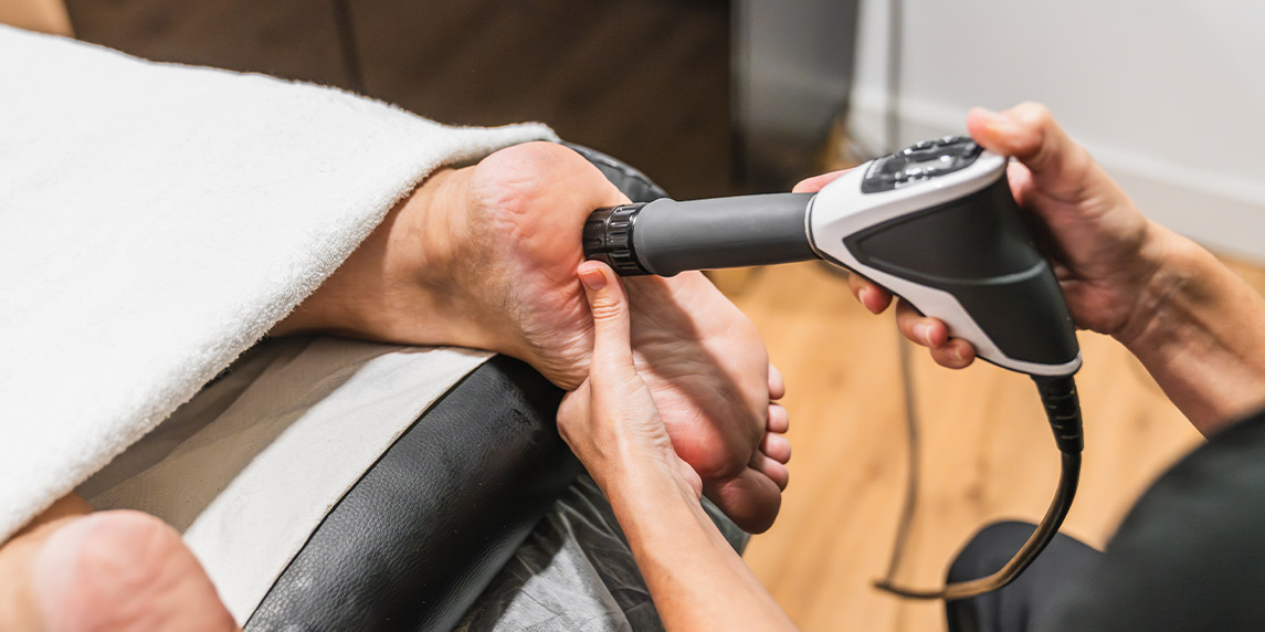 Individual enjoying a foot massage with an ESWT shockwave machine, illustrating the use of ESWT machines for relaxation.